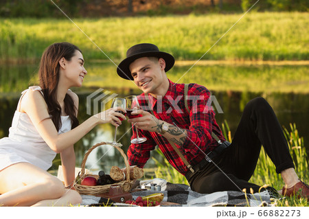 Caucasian young and happy couple enjoying a picnic in the park on summer day Caucasian young and happy couple enjoying a picnic in the park on summer day 66882273