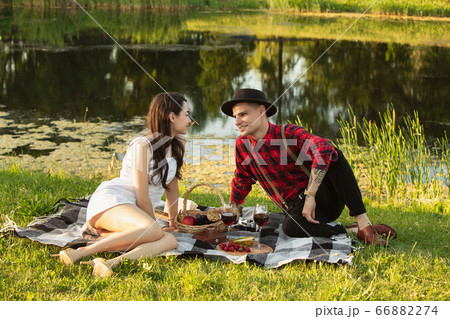 Caucasian young and happy couple enjoying a picnic in the park on summer day Caucasian young and happy couple enjoying a picnic in the park on summer day 66882274