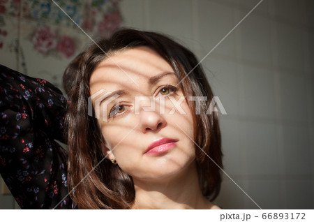 Female indoors portrait of young brunette woman with makeup and sensual lips at home on white tiles background on the kitchen Female indoors portrait of young brunette woman with makeup and sensual lips at home on white tiles background on the kitchen 66893172