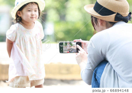 砂場で遊ぶ子供をスマートフォンで撮影する母親 66894148