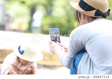砂場で遊ぶ子供をスマートフォンで撮影する母親 砂場で遊ぶ子供をスマートフォンで撮影する母親 66897319