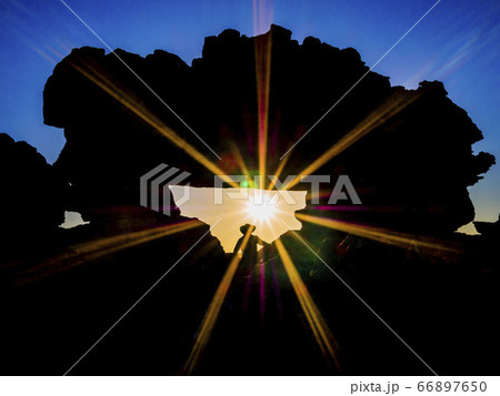 Tourist enjoying taking pictures at sunset at the famous rock formation called La Fenetre, Isalo National Park, Madagascar Tourist enjoying taking pictures at sunset at the famous rock formation called La Fenetre, Isalo National Park, Madagascar 66897650
