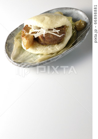 レタスが敷いてあるお皿に置かれた白髪ねぎも一緒に挟まったシンプルな角煮まんと和がらし（白背景） 66898881