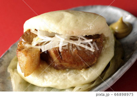 レタスが敷いてあるお皿に置かれた白髪ねぎも一緒に挟まったシンプルな角煮まんと和がらし レタスが敷いてあるお皿に置かれた白髪ねぎも一緒に挟まったシンプルな角煮まんと和がらし 66898975