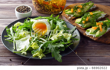 Fresh green salad with egg and crispbreads with cheese on wooden backdrop. 66902022