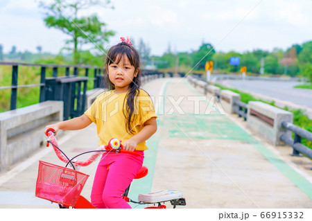 Little child girl to ride bicycle in outdoor sports ground on sunny summer day. Little child girl to ride bicycle in outdoor sports ground on sunny summer day. 66915332