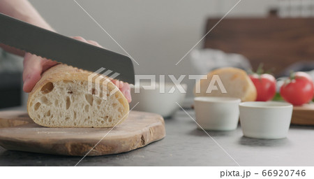 man slicing ciabatta bread on olive wood board man slicing ciabatta bread on olive wood board 66920746