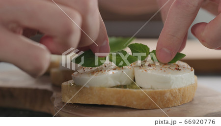 man decorating bruschetta with pesto and mozzarella on olive board 66920776