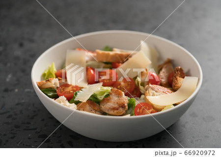 Fresh caesar salad with chicken and cherry tomatoes in white bowl 66920972