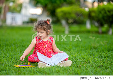 Little  girl learning for coloring or drawing paint on green grass in nature at garden 66921593