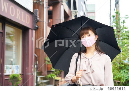 時差出勤　雨天　マスクをして傘をさすビジネスウーマン　出勤　通勤　外出　 66923613
