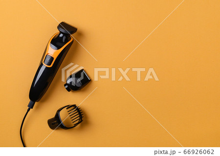 Electric black hair clipper or trimmer on a textured yellow background with copy space. Electric black hair clipper or trimmer on a textured yellow background with copy space. 66926062