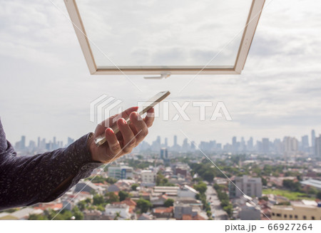 A man uses a phone against the backdrop of a panorama of a metropolis. A man uses a phone against the backdrop of a panorama of a metropolis. 66927264