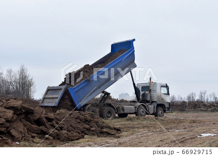 Dump truck dumps its load of sand and ground on construction site for road construction 66929715