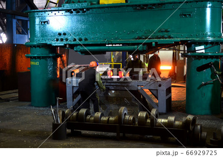 Blacksmith processes the red hot iron under a huge press Blacksmith processes the red hot iron under a huge press 66929725