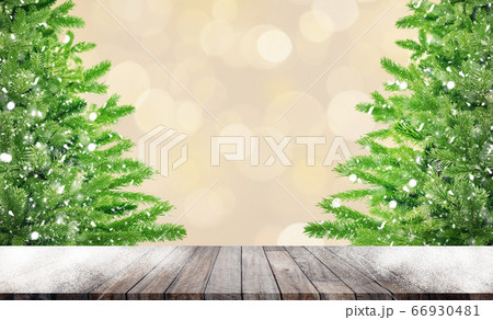 Wooden table and Green pine tree toy model with falling white snow in bokeh background. 66930481