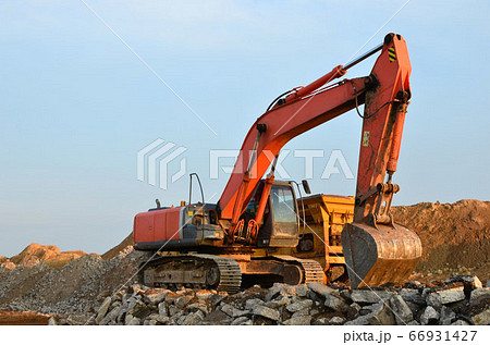 Excavator in a working at granite quarry unloads old concrete stones for crushing and recycling 66931427