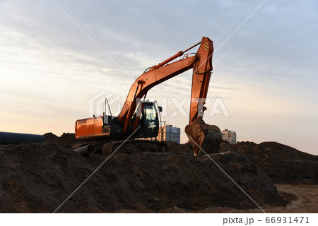 Red excavator at building under construction against the background sunset Red excavator at building under construction against the background sunset 66931471