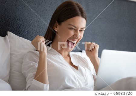 Excited woman scream winning lottery on laptop 66933720