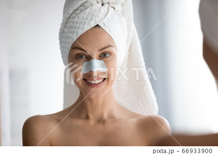 Portrait of woman cleansing face pores with nose patches 66933900