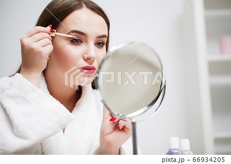 Pretty girl applies makeup on her face in the hotel bathroom Pretty girl applies makeup on her face in the hotel bathroom 66934205