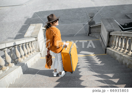 Woman traveling with a suitcase in the old city 66935803