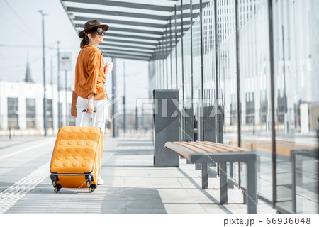Young female traveler with a luggage at the transport stop 66936048