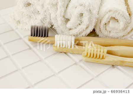 Family set of tree bamboo toothbrushes, white towels on tile background. Eco friendly concept Family set of tree bamboo toothbrushes, white towels on tile background. Eco friendly concept 66936413