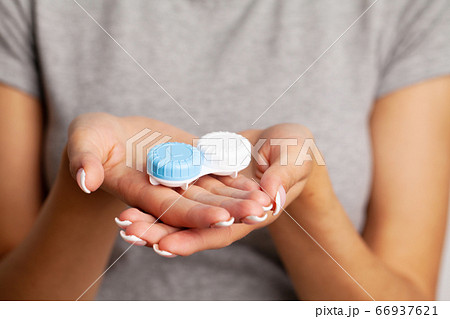 Vision problems, close up of woman holding container with contact lenses Vision problems, close up of woman holding container with contact lenses 66937621
