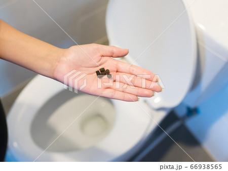 Woman hands holding laxatives pill and using toilet and suffers from diarrhea and hemorrhoids after wake up in the morning 66938565