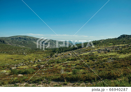 Hilly landscape covered by green fields and rocks Hilly landscape covered by green fields and rocks 66940287