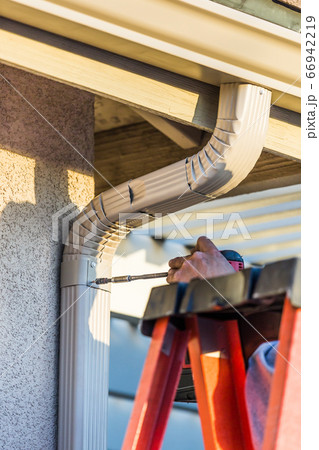 Worker Attaching Aluminum Rain Gutter and Down Spout 66942219