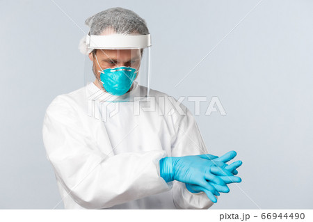 Covid-19, virus, healthcare workers and vaccination concept. Doctor in personal protective equipment put on rubber gloves before entering patient ward with people sick on coronavirus disease 66944490