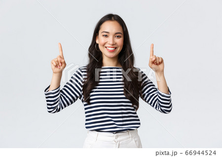 Lifestyle, beauty and fashion, people emotions concept. Cheerful good-looking female model pointing fingers up to shop promotion banner, smiling camera, recommend click link to online store 66944524