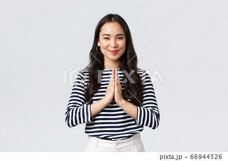 Lifestyle, people emotions and casual concept. Cute asian girl in casual outfit smiling as saying namaste, holding hands in pray, pleading or greeting guests with polite bow 66944526