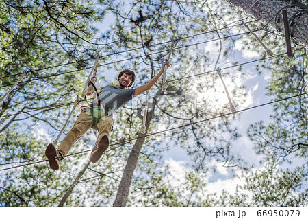 Young attractive man in adventure rope park in safety equipment 66950079