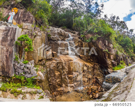 Motorcyclist rides on a serpentine road in cloudy weather. Vietnam, Dalat 66950525