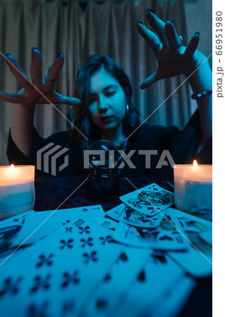 Woman fortune-teller guesses fate of night at table with candles 66951980