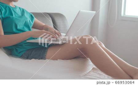 Young asian woman sitting on the bed checking social apps and working on laptop computer in the bedroom while working from home. stay at home concept. 66953064