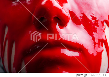 Image of a female's face with spreading glossy red paint 66953244