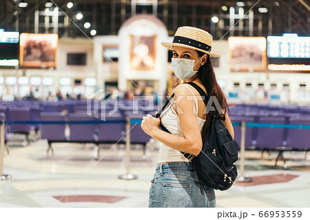 Brunette girl traveler in train station wearing a face mask and summer clothes 66953559