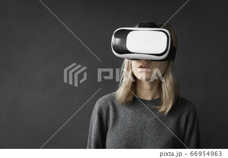 Young woman wearing virtual reality goggles headset, vr box. Connection, technology, new generation, progress concept. Girl trying to touch objects in virtual reality. 66954963