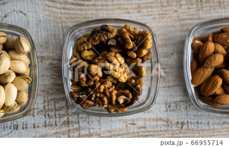 Almond, pistachio and walnut in a small plates which standing on a vintage white table. Nuts is a healthy vegetarian protein and nutritious food. Almond, pistachio and walnut in a small plates which standing on a vintage white table. Nuts is a healthy vegetarian protein and nutritious food. 66955714