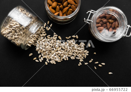 Sunflower seeds scattered on the black table from a jar. Sunflower seed is a healthy vegetarian protein nutritious food. Sunflower seeds scattered on the black table from a jar. Sunflower seed is a healthy vegetarian protein nutritious food. 66955722