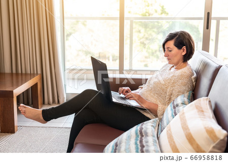 Middle-aged woman in the living room at the computer. Sunny day. 66958818