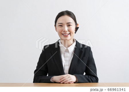 ヘッドセットをつけてカメラ目線で話す スーツ姿の若い女性 ヘッドセットをつけてカメラ目線で話す スーツ姿の若い女性 66961341