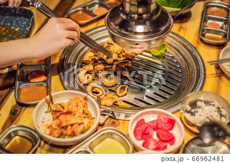Woman grilling barbecue on mesh grill of charcoal fire. Korean or japanese traditional food grilling 66962481