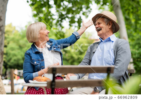 Happy senior couple sitting outdoors in cafe, talking. 66962809