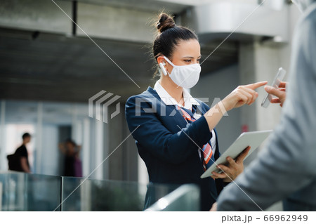 Flight attendant talking to businessman on airport, wearing face mask. Flight attendant talking to businessman on airport, wearing face mask. 66962949
