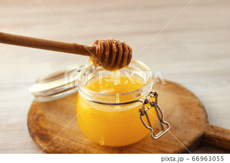 Honey dripping from a wooden dipper in jar on old Honey dripping from a wooden dipper in jar on old 66963055